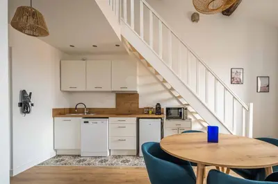 a kitchen with a table and blue chairs and a staircase at Le Chenal - Appartement Duplex proche des halles in Narbonne