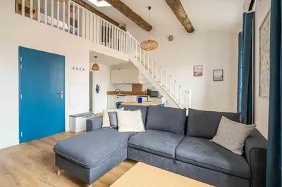 a living room with a blue couch and stairs at Le Chenal - Appartement Duplex proche des halles in Narbonne