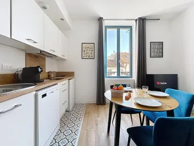 a kitchen with a table and chairs and a window at L'Alcazar - Appartement à deux pas des halles - Climatisation in Narbonne