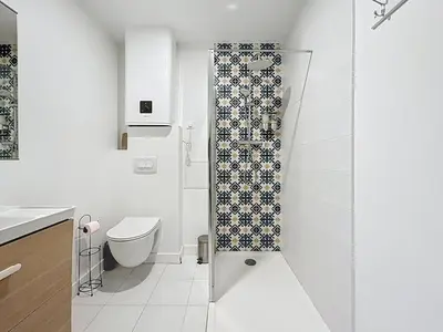 a white bathroom with a shower and a toilet at L'Alcazar - Appartement à deux pas des halles - Climatisation in Narbonne