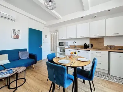 a kitchen and dining room with a table and blue chairs at L'Alcazar - Appartement à deux pas des halles - Climatisation in Narbonne