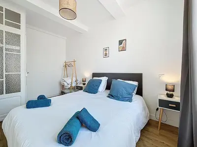 a bedroom with a large white bed with blue pillows at L'Alcazar - Appartement à deux pas des halles - Climatisation in Narbonne
