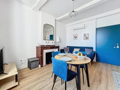 a living room with a table and blue chairs at L'Alcazar - Appartement à deux pas des halles - Climatisation in Narbonne