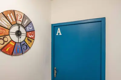 a clock on a wall next to a blue door at L'Alcazar - Appartement à deux pas des halles - Climatisation in Narbonne