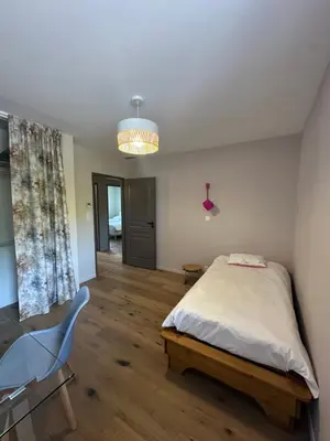 a bedroom with a bed and a chair and a chandelier at La remise d'Edouard in Saint-Papoul