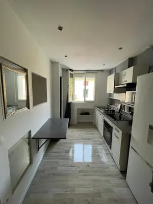a kitchen with white cabinets and a wooden floor at Appartement dans le village à port la nouvelle in Port-la-Nouvelle