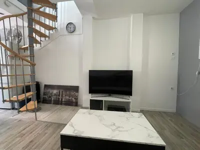 a living room with a television and a staircase at Appartement dans le village à port la nouvelle in Port-la-Nouvelle