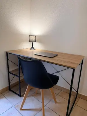 a desk with a laptop and a chair with a lamp at Sunny Pearl - Spacieux Appartement Climatisé au Centre ville in Narbonne
