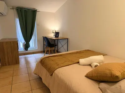 a bedroom with a bed and a desk with a chair at Sunny Pearl - Spacieux Appartement Climatisé au Centre ville in Narbonne