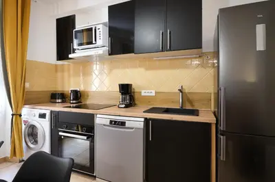 a kitchen with a sink and a refrigerator at Sunny Pearl - Spacieux Appartement Climatisé au Centre ville in Narbonne