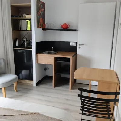 a small kitchen with a wooden desk and a table at Le Logis de la Voie Verte in Saint-Amadou