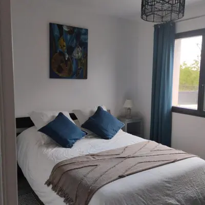 a bedroom with a bed with blue pillows on it at Le Logis de la Voie Verte in Saint-Amadou