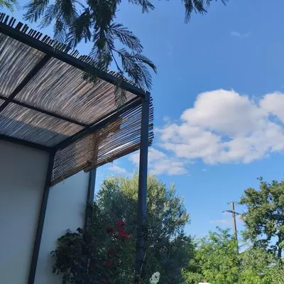 awning on a building with trees in the background at Le Logis de la Voie Verte in Saint-Amadou