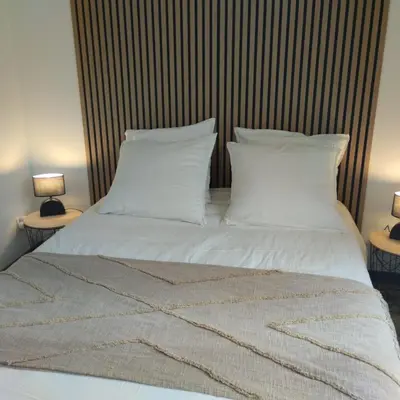a large bed with white sheets and pillows at Le Logis de la Voie Verte in Saint-Amadou