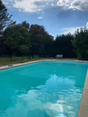 a pool of blue water with trees in the background at Dépendance paisible in Ventenac-Cabardès