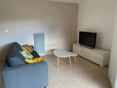 a living room with a blue couch and a tv at Dépendance paisible in Ventenac-Cabardès