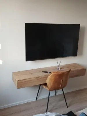 a desk with a television on a wall with a chair at La maison des moments in Carcassonne