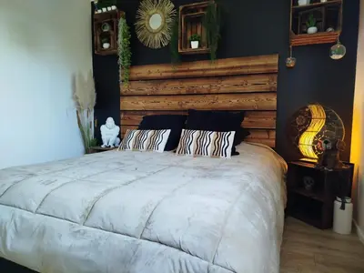 a bedroom with a large bed with a wooden headboard at La maison des moments in Carcassonne
