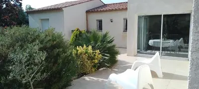 a garden with white chairs and a table on a patio at Maison dans le sud au calme avec extérieur in Ferrals-lès-Corbières