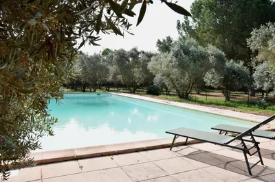 a swimming pool with a table and a bench at Villa Les Charmes in Narbonne