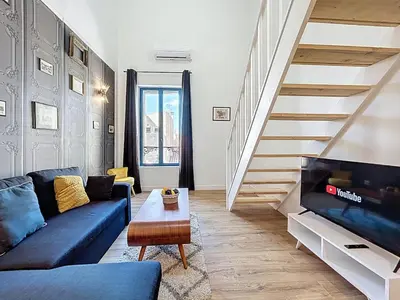 a living room with a blue couch and a staircase at Le Datrio - Appartement proche des halles - Wifi et climatisation in Narbonne