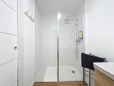 a white bathroom with a shower with a glass door at Le Datrio - Appartement proche des halles - Wifi et climatisation in Narbonne