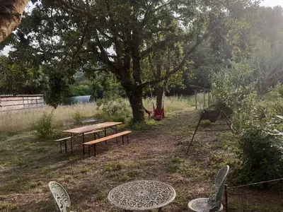 a picnic table and chairs in a yard with a tree at Gîte à la ferme in Montolieu