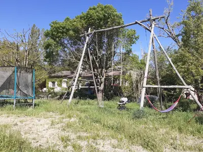 an old swing set in a field with a house at Gîte à la ferme in Montolieu