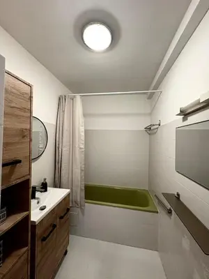 a bathroom with a green bath tub and a sink at Appartement T2 in Port-la-Nouvelle