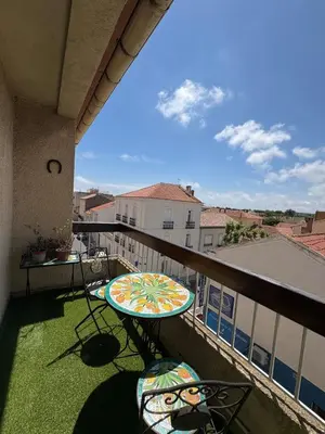 a balcony with a table and chairs on the grass at Appartement T2 in Port-la-Nouvelle