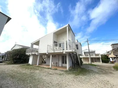a large white house with a staircase in front of it at Chalet climatisé 5 personnes Gruissan plage in Gruissan