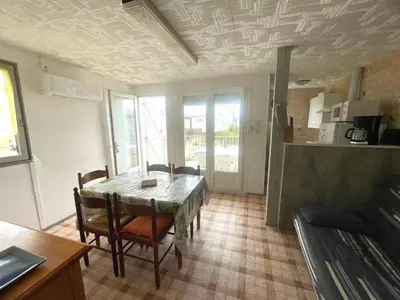 a kitchen and dining room with a table and chairs at Chalet climatisé 5 personnes Gruissan plage in Gruissan