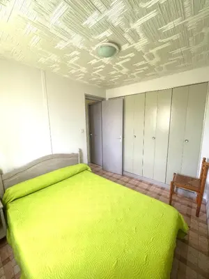 a bedroom with a green bed and a chair at Chalet climatisé 5 personnes Gruissan plage in Gruissan