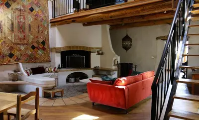 a living room with a red couch and a fireplace at La Terrasse aux citronniers in Saint-Vincent