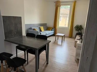 a living room with a table and a couch at Appartement centre-ville Narbonne 5 personnes, climatisé, 2 chambres in Narbonne
