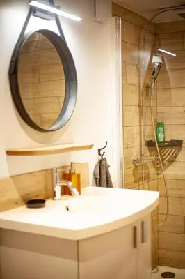 a bathroom with a sink and a shower with a mirror at Chambre Studio B&B in Mazamet