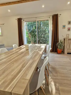a large wooden table with white chairs in a room at Le Gîte du Parc in Roubia