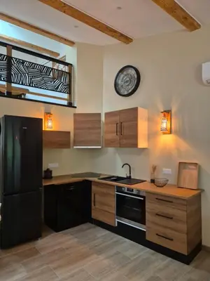 a kitchen with a black refrigerator and a clock on the wall at Le Gîte du Parc in Roubia