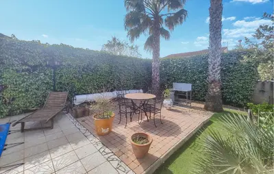 a patio with a table and chairs and palm trees at Nice Home In Cessenon Sur Orb - Flh677 in Cessenon