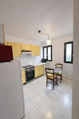 a kitchen with yellow cabinets and a table and chairs at Spacieux appartement Coeur du Village Wifi Draps in Gruissan