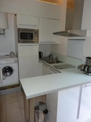 a white kitchen with a sink and a microwave at Apartment with large terrace, ground floor in Narbonne
