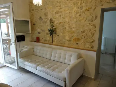 a couch in a living room with a stone wall at Apartment with large terrace, ground floor in Narbonne