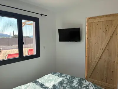 a bedroom with a sliding door and a tv on the wall at villa de vacances in Cessenon