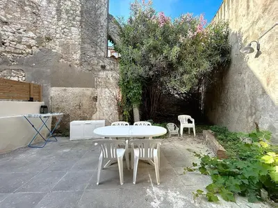 a white table and chairs in a courtyard at Le Rousseau - Comfortable apartment - Wi-Fi in Salles-d'Aude