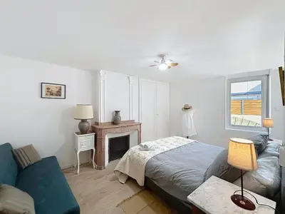 a bedroom with a bed and a couch and a fireplace at Le Lies - Appartement proche de la mer in Salles-d'Aude