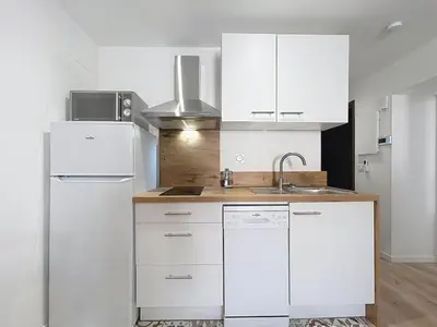 a white kitchen with a sink and a refrigerator at Le Lies - Appartement proche de la mer in Salles-d'Aude