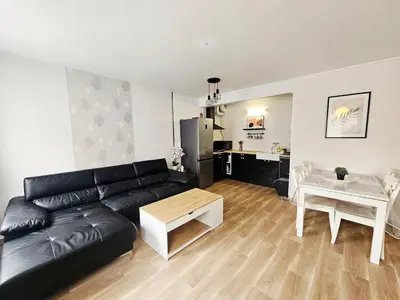 a living room with a black leather couch and a table at Maison de vacances en Ariège in La Bastide-de-Bousignac