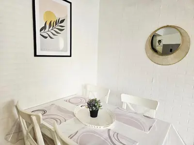 a white dining room with a table and a mirror at Maison de vacances en Ariège in La Bastide-de-Bousignac