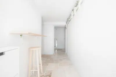 a hallway with a stool and a white wall at Ambiance sudiste , piscine, boule, farniente AG in Carcassonne