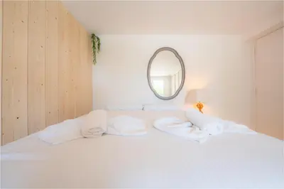a white bed with white pillows and a mirror at Ambiance sudiste , piscine, boule, farniente AG in Carcassonne